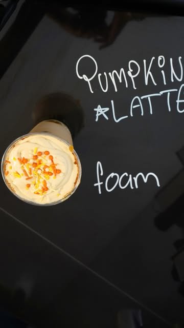 Pumpkin Latte visto desde arriba con foam de calabaza y chispas naranjas junto a la palabra Pumpkin Latte escrita a mano