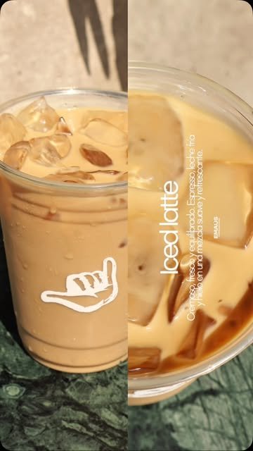 Iced latte de EMAÚS en vaso transparente con el shaka impreso, cubos de hielo y leche con espresso, sobre mármol verde