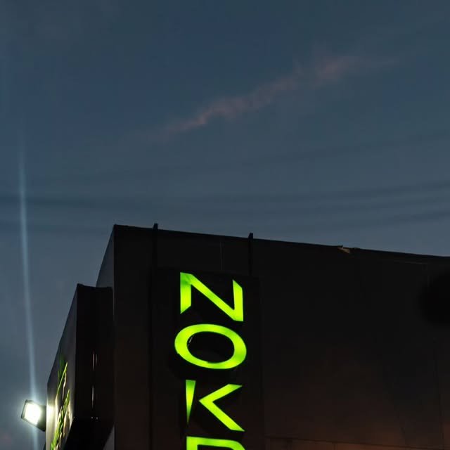 Letrero luminoso verde de NOKRYPT sobre el edificio al atardecer